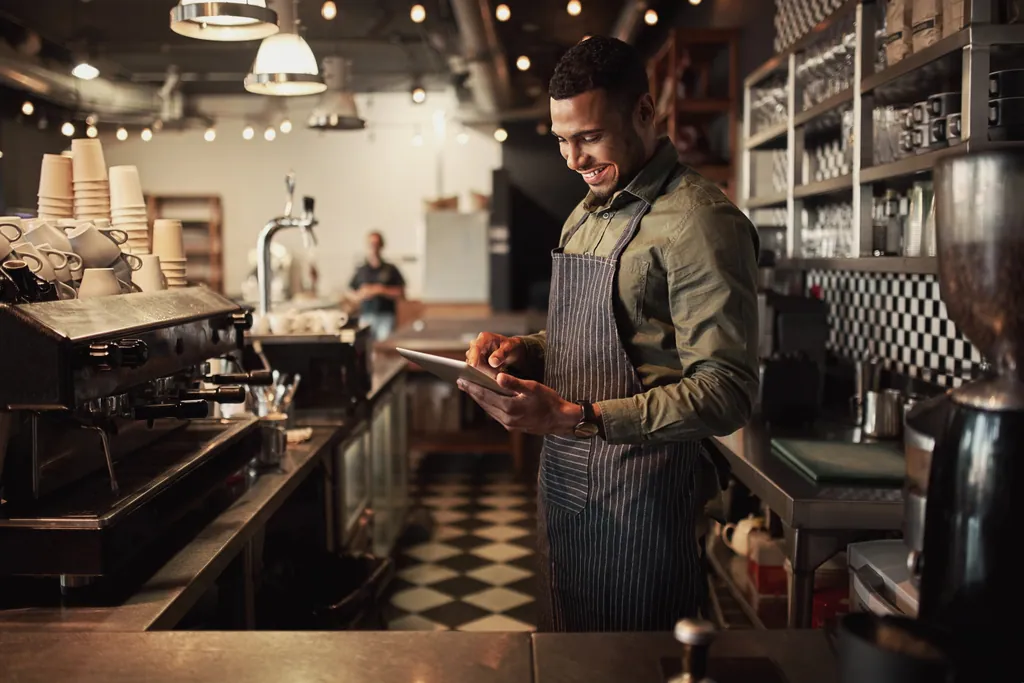 Café owner checking orders on a tablet behind the counter